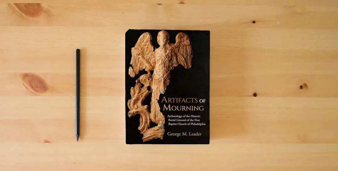 The book Artifacts of Mourning: Archaeology of the Historic Burial Ground of the First Baptist Church of Philadelphia (Studies in Funerary Archaeology)} is on the table