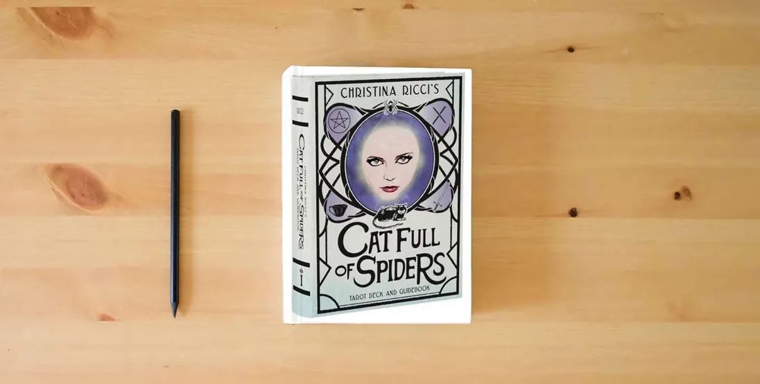 The book Christina Ricci's Cat Full of Spiders Tarot Deck and Guidebook} is on the table