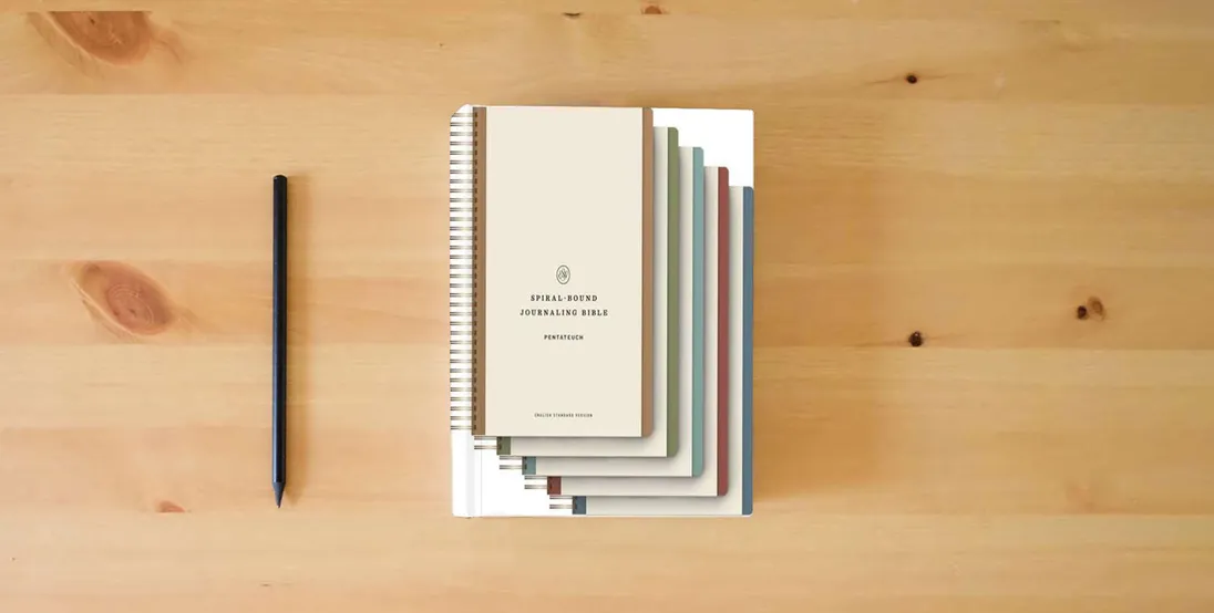 The book ESV Spiral-Bound Journaling Bible, Five-Volume Set (Hardcover)} is on the table