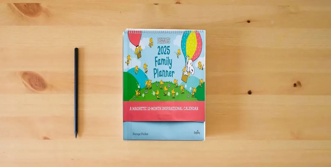 The book Peanuts: 2025 Inspirational Family Planner} is on the table