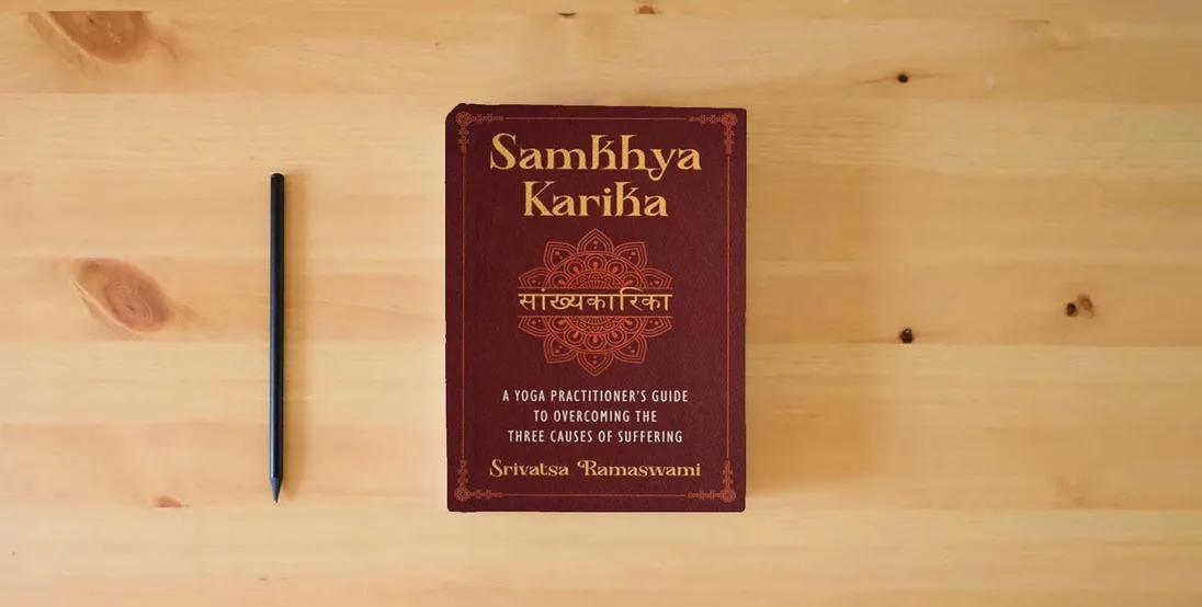 The book Samkhya Karika: A Yoga Practitioner's Guide to Overcoming the Three Causes of Suffering} is on the table